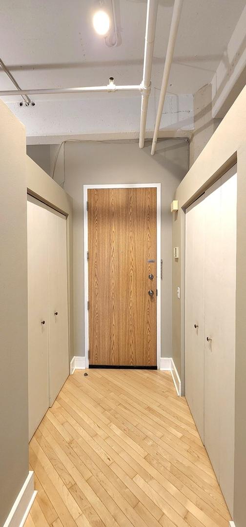 hall featuring light wood-type flooring and baseboards