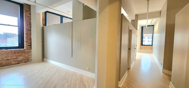 hallway with brick wall, a high ceiling, and light wood-type flooring