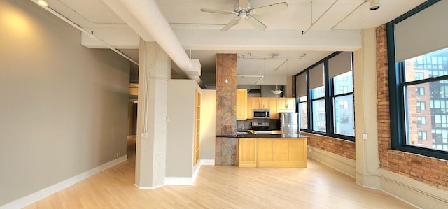 kitchen with stainless steel appliances, brick wall, a healthy amount of sunlight, light brown cabinetry, and light wood finished floors