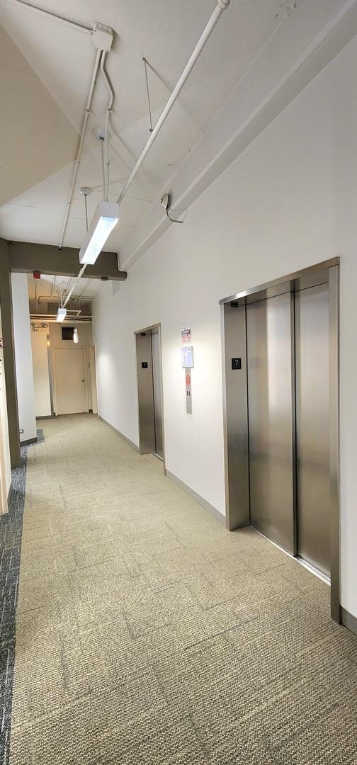 interior space with baseboards, carpet flooring, and elevator