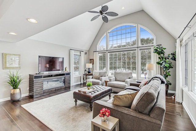 living area featuring high vaulted ceiling, dark wood-type flooring, visible vents, and baseboards