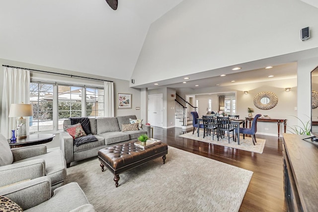 living room with high vaulted ceiling, recessed lighting, wood finished floors, baseboards, and stairway