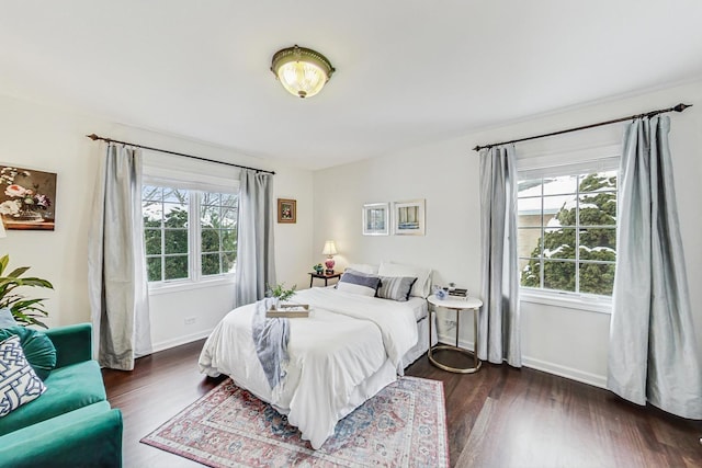 bedroom with multiple windows, baseboards, and dark wood finished floors