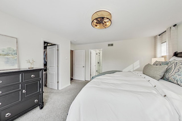 bedroom with carpet floors, visible vents, baseboards, and a walk in closet