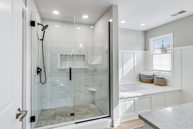 bathroom featuring a stall shower, visible vents, a decorative wall, and wainscoting