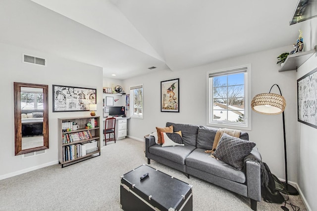 carpeted living room featuring baseboards, visible vents, vaulted ceiling, and a wealth of natural light