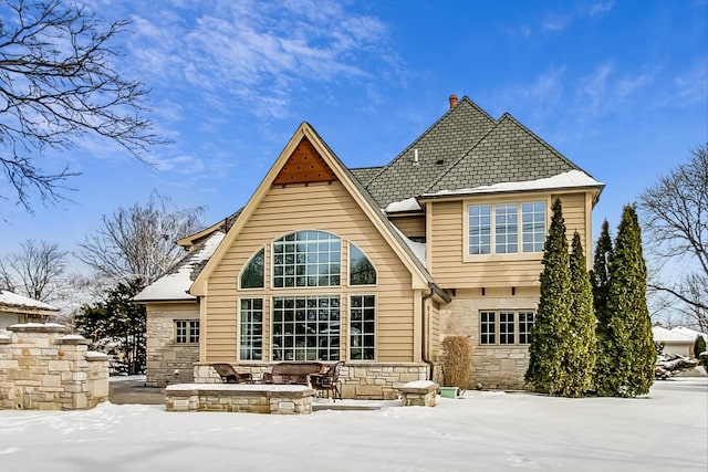 snow covered house featuring stone siding