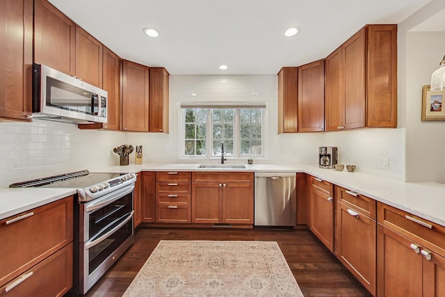 kitchen with appliances with stainless steel finishes, dark wood finished floors, light countertops, and a sink