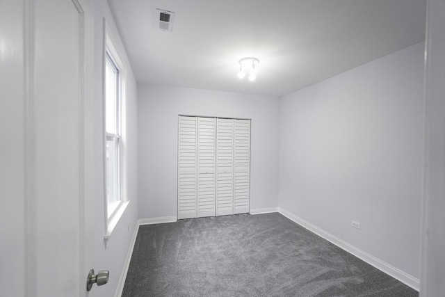 unfurnished bedroom featuring dark carpet and a closet