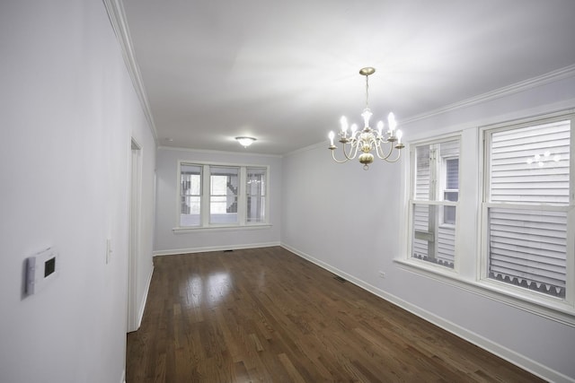 empty room featuring dark hardwood / wood-style flooring, ornamental molding, and an inviting chandelier