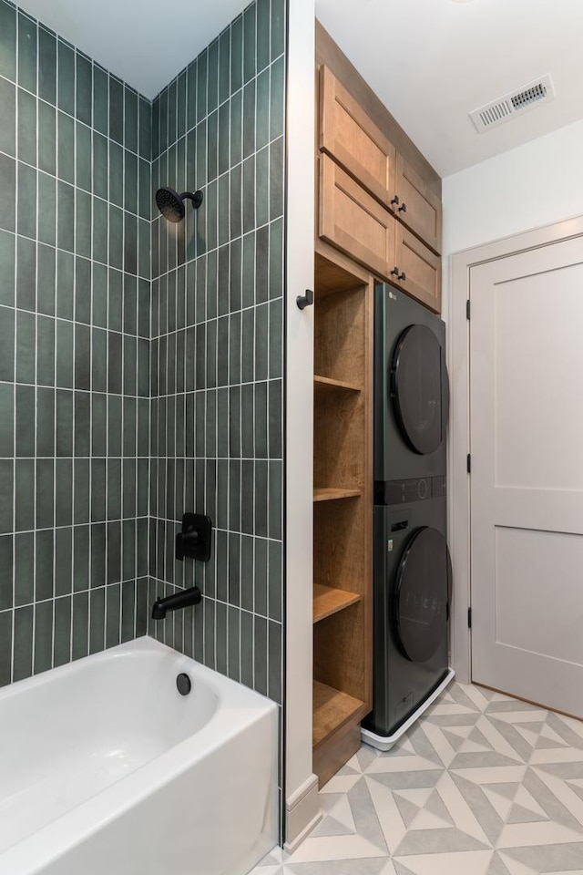 bathroom with tiled shower / bath combo and stacked washer / dryer