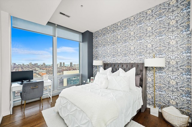 bedroom with a wall of windows and dark hardwood / wood-style floors