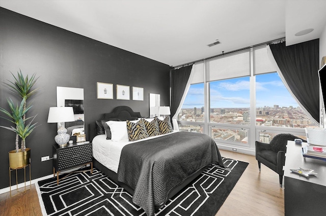 bedroom with wood-type flooring and expansive windows