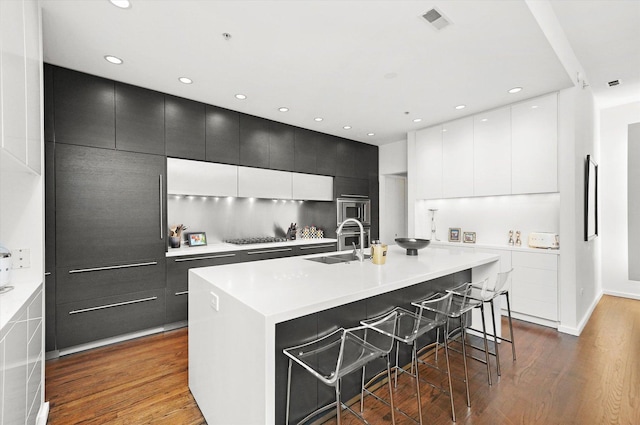 kitchen featuring a spacious island, a breakfast bar, gas stovetop, and hardwood / wood-style flooring