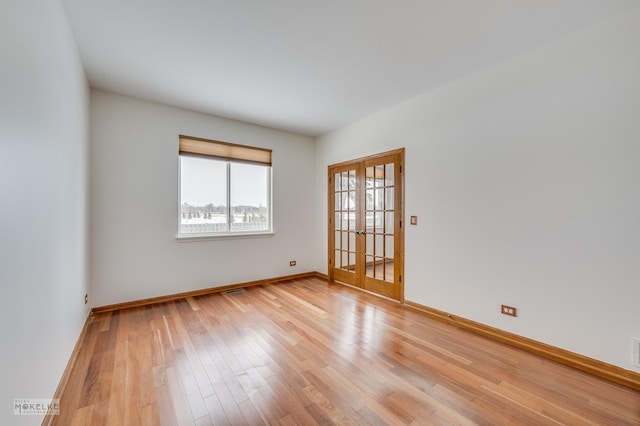 unfurnished room featuring french doors and light wood-type flooring