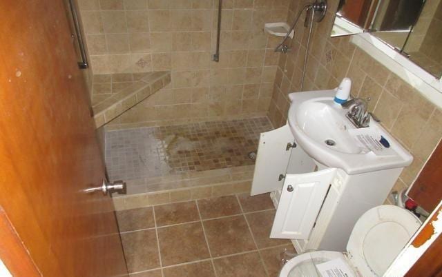 bathroom with vanity, a tile shower, tile patterned floors, and tile walls