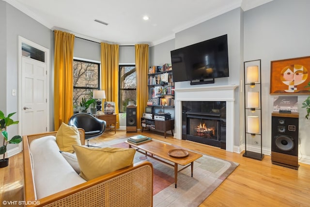 living room featuring a tile fireplace, ornamental molding, and hardwood / wood-style flooring