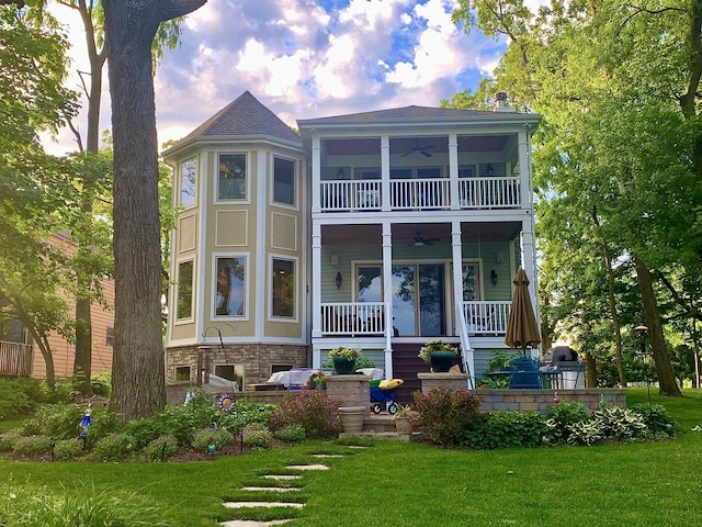 rear view of property featuring a yard, ceiling fan, and a porch