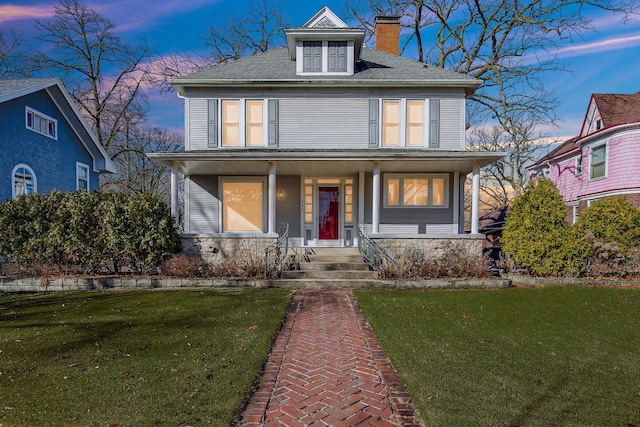 view of front of property with covered porch and a lawn