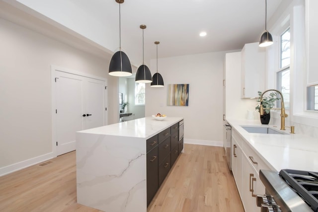 kitchen featuring white cabinetry, decorative light fixtures, a center island, and sink