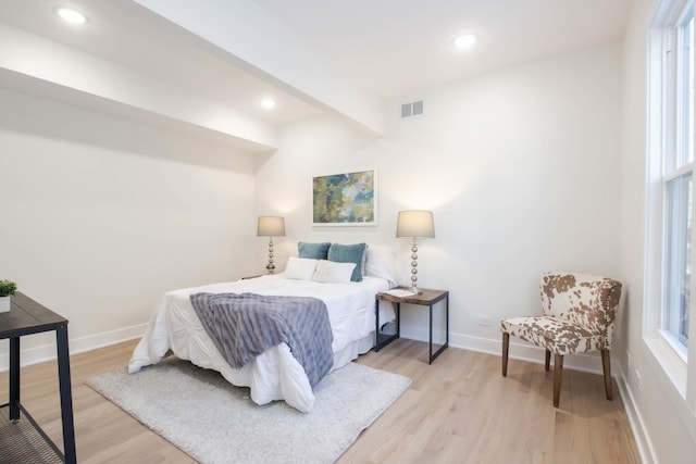 bedroom featuring beam ceiling and light hardwood / wood-style floors