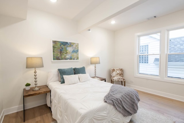 bedroom with beamed ceiling and light wood-type flooring