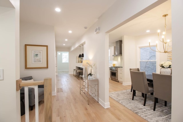 hallway featuring an inviting chandelier and light hardwood / wood-style floors