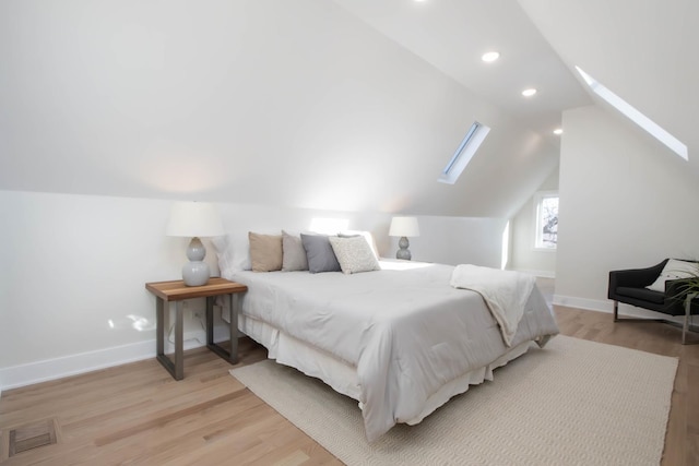 bedroom with vaulted ceiling with skylight and light hardwood / wood-style floors