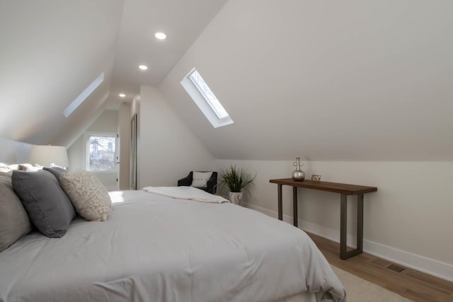 bedroom with vaulted ceiling with skylight and light wood-type flooring