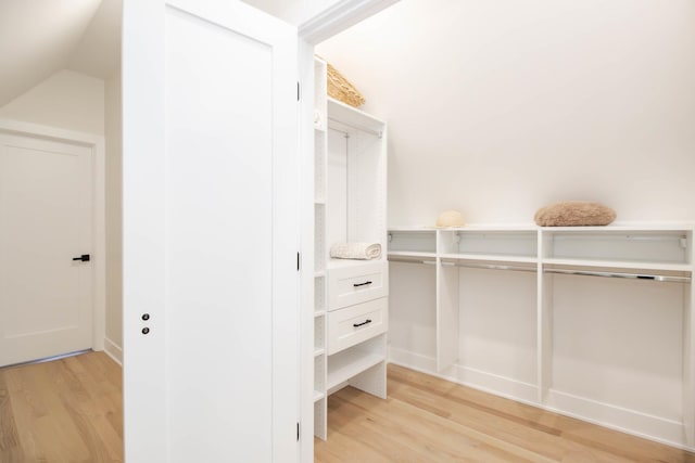 walk in closet with vaulted ceiling and light hardwood / wood-style flooring