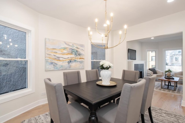 dining area with light hardwood / wood-style floors and a notable chandelier