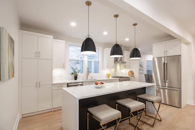 kitchen with stainless steel appliances, white cabinetry, a center island, and sink