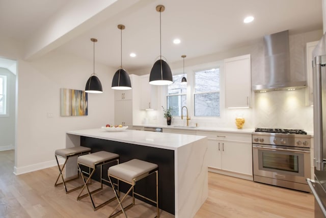 kitchen featuring a kitchen island, stainless steel stove, sink, white cabinets, and wall chimney exhaust hood