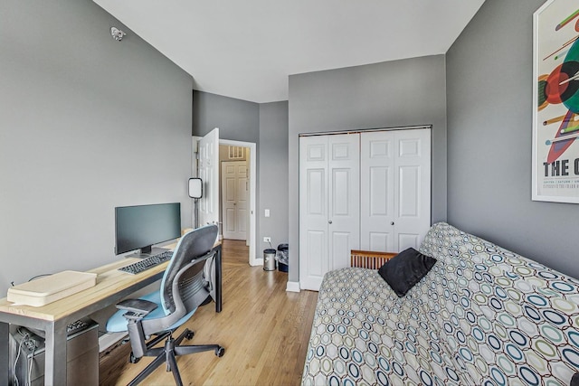 bedroom featuring light wood-type flooring, a closet, and baseboards