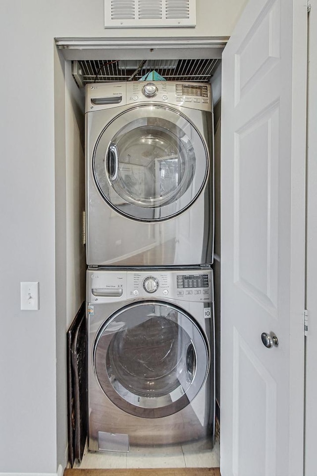 laundry area with laundry area, visible vents, and stacked washing maching and dryer