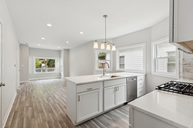 kitchen featuring decorative light fixtures, stainless steel dishwasher, open floor plan, white cabinetry, and a sink