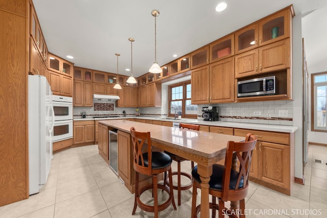 kitchen with sink, stainless steel appliances, a center island, decorative light fixtures, and beverage cooler