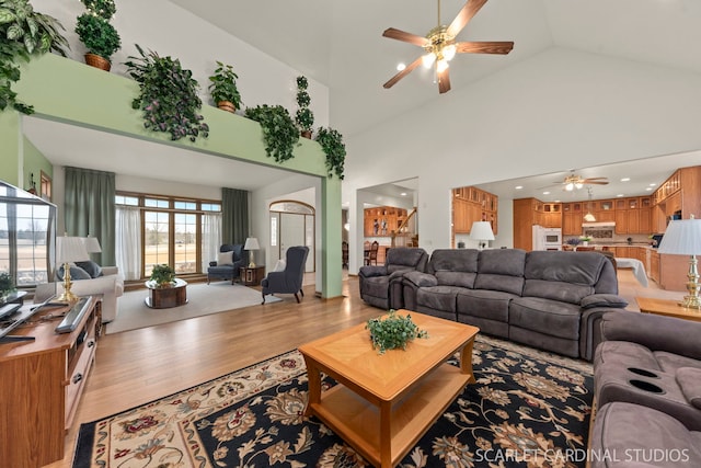 living room with high vaulted ceiling, ceiling fan, and light hardwood / wood-style flooring