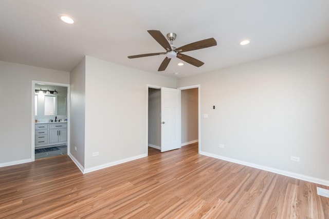 unfurnished bedroom featuring ceiling fan, sink, ensuite bath, and light hardwood / wood-style flooring