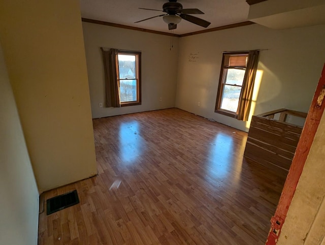 spare room with hardwood / wood-style floors, crown molding, a wealth of natural light, and ceiling fan