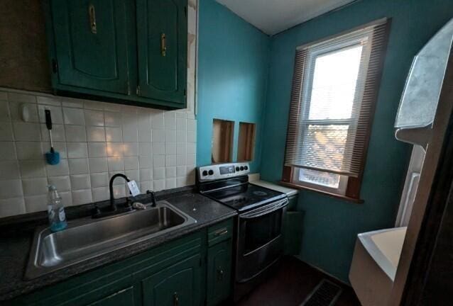 kitchen featuring tasteful backsplash, electric range oven, sink, and green cabinetry