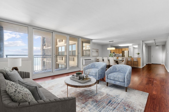 living area with baseboards, an AC wall unit, and wood finished floors