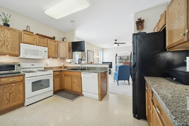 kitchen featuring white appliances, sink, dark stone counters, ceiling fan, and kitchen peninsula