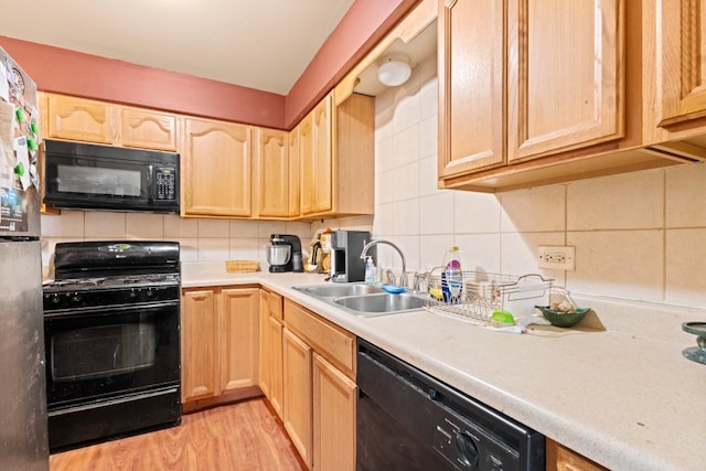 kitchen with tasteful backsplash, light countertops, light brown cabinets, a sink, and black appliances