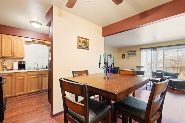 dining space featuring dark wood-style floors, beam ceiling, a wall unit AC, and ceiling fan