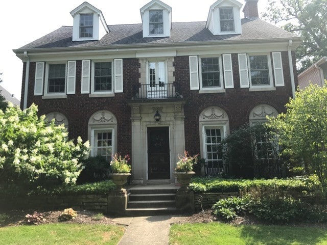 colonial home featuring a balcony and brick siding