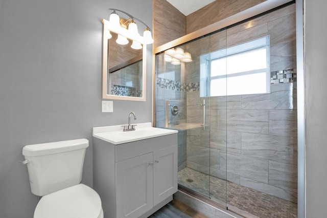 bathroom featuring vanity, toilet, and a shower with shower door