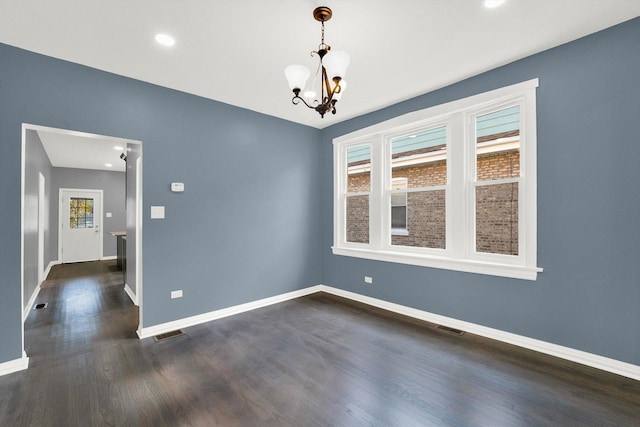 unfurnished room featuring dark wood-type flooring, a wealth of natural light, and a notable chandelier