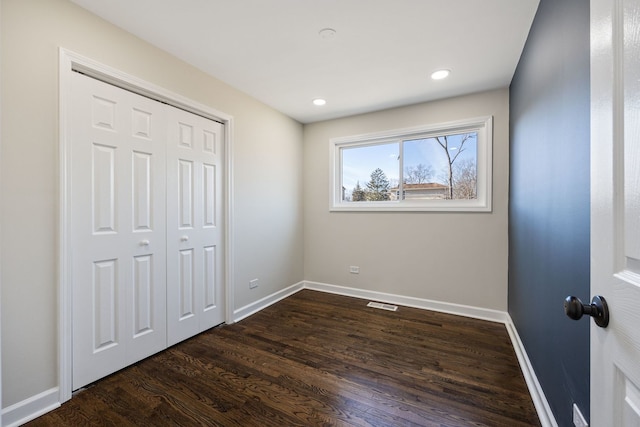 unfurnished bedroom with dark hardwood / wood-style flooring and a closet