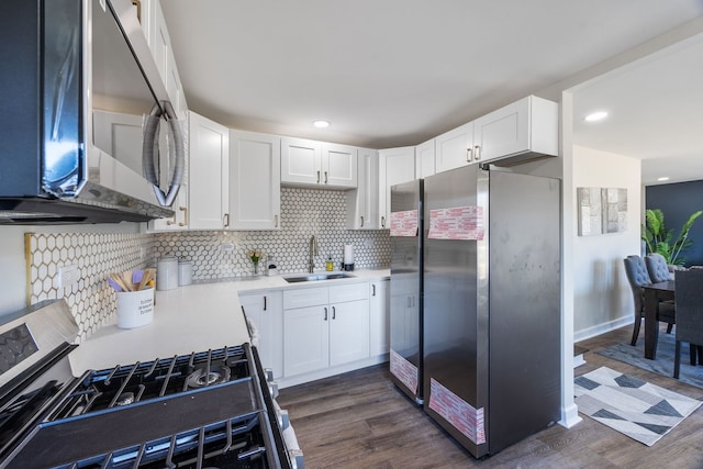 kitchen featuring sink, dark hardwood / wood-style floors, white cabinets, stainless steel appliances, and backsplash